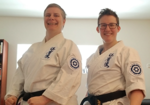 Amy & Kyren in karate uniforms smiling at the camera